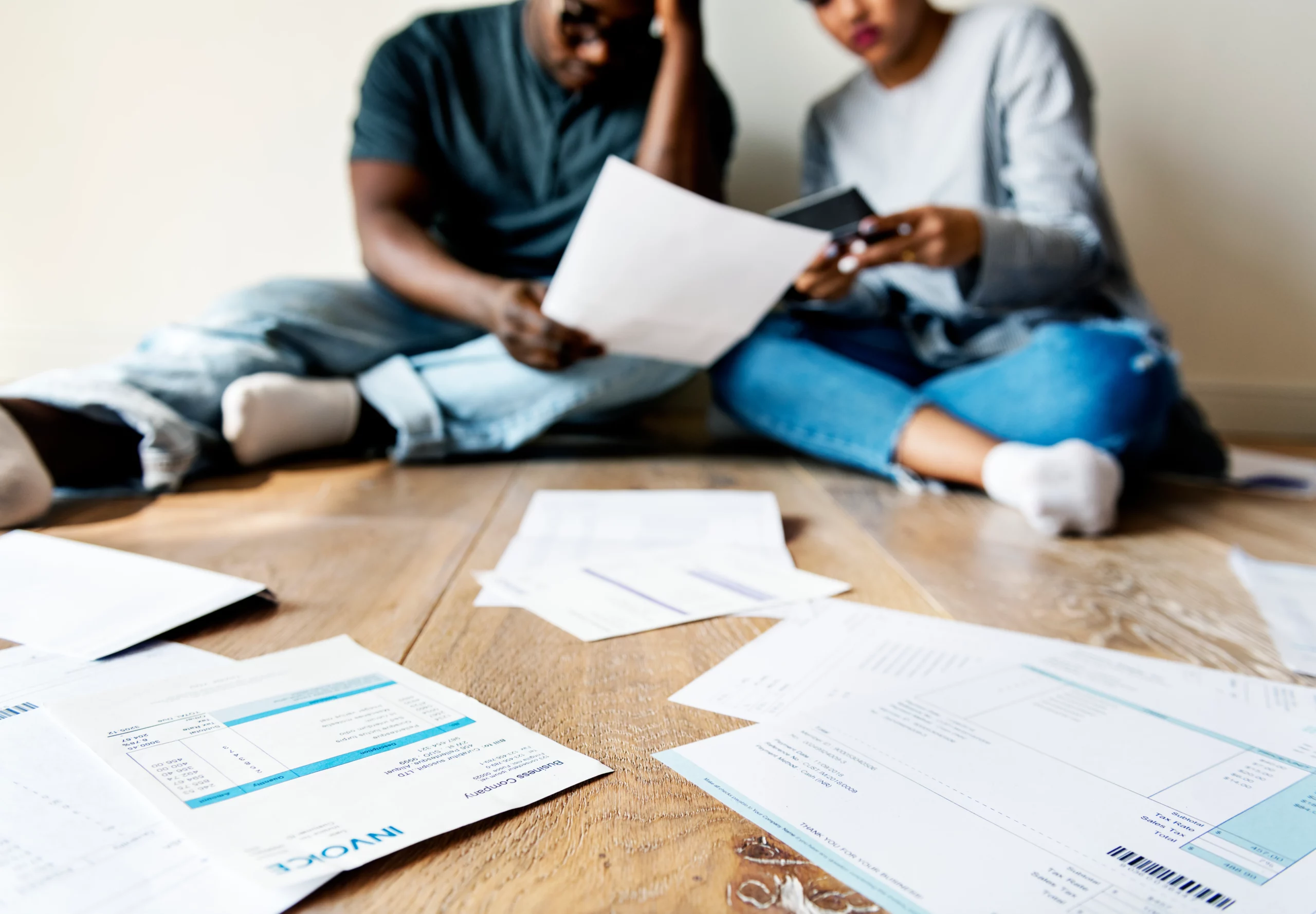 Worried couple surrounded by bills and smartphone, illustrating married couples considering separate Chapter 7 bankruptcy filing in Florida.